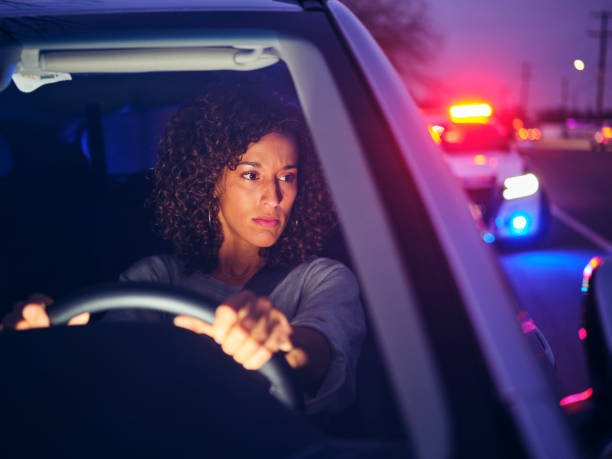 A young woman, being stopped by police at night for a traffic violation.